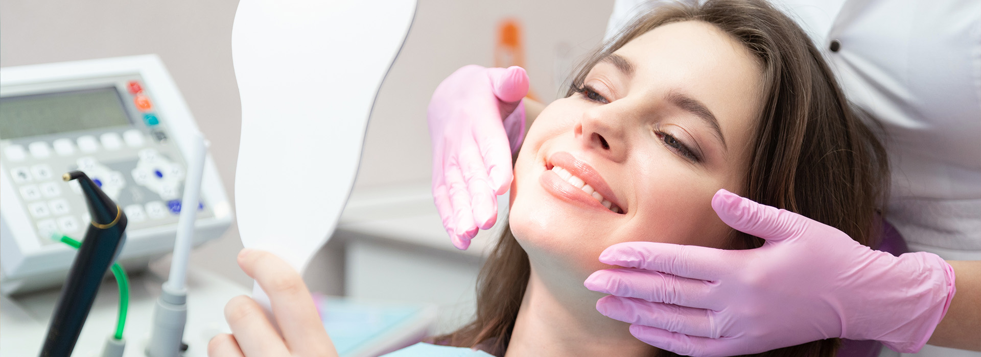 A woman receiving dental care while seated in a dentist s chair she is wearing a purple surgical mask, and there are medical instruments around her neck.