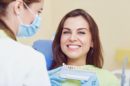 The image depicts a woman receiving dental care from a professional at a dental clinic, with both smiling.